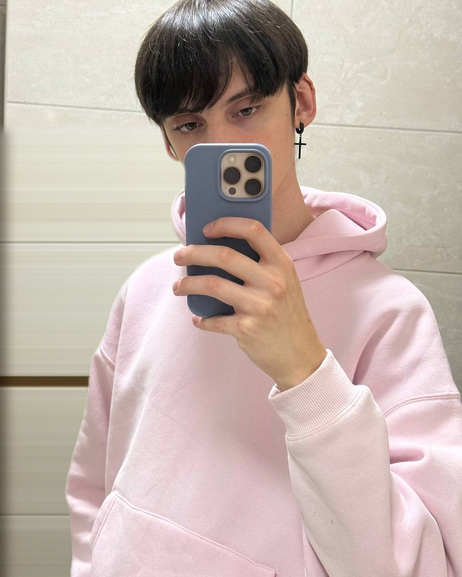 Anton Demianov in a pink hoodie taking a mirror selfie